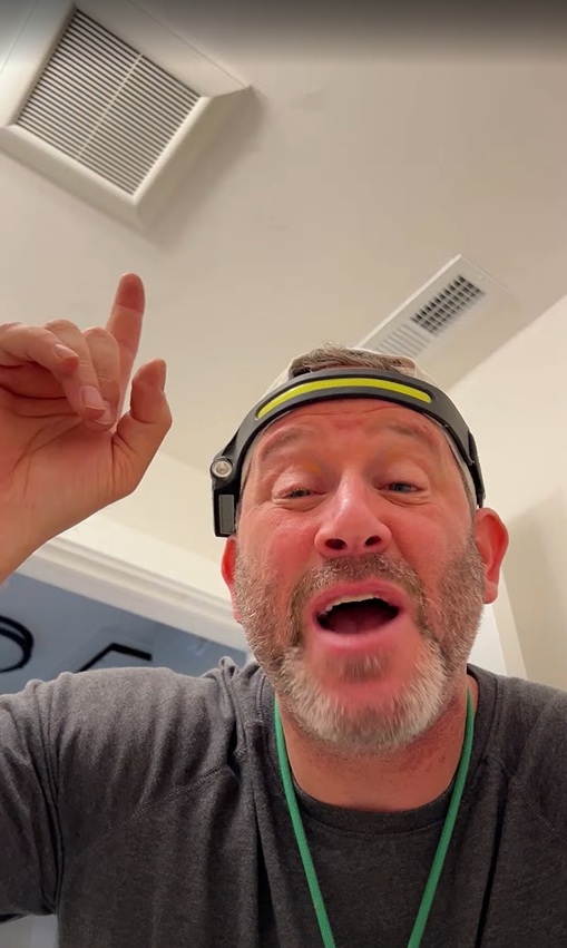 Eric Gans pointing toward a bathroom exhaust fan grille