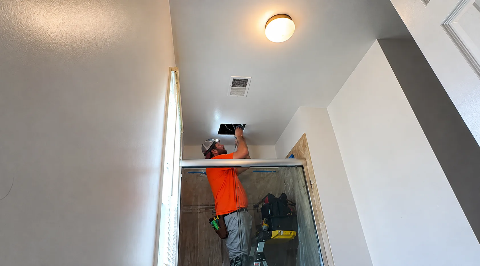Eric Gans working with a bathroom exhaust fan during a field installation