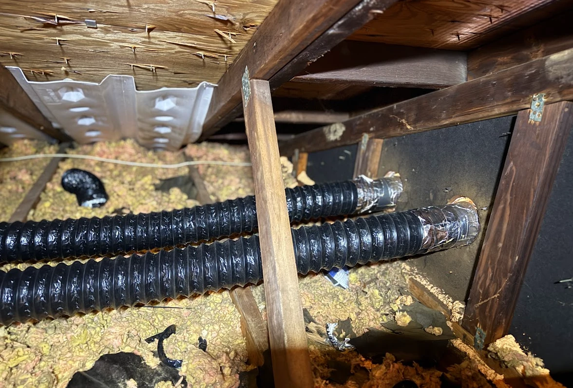 Two bathroom exhaust fans routed through a gable wall before being buried in insulation