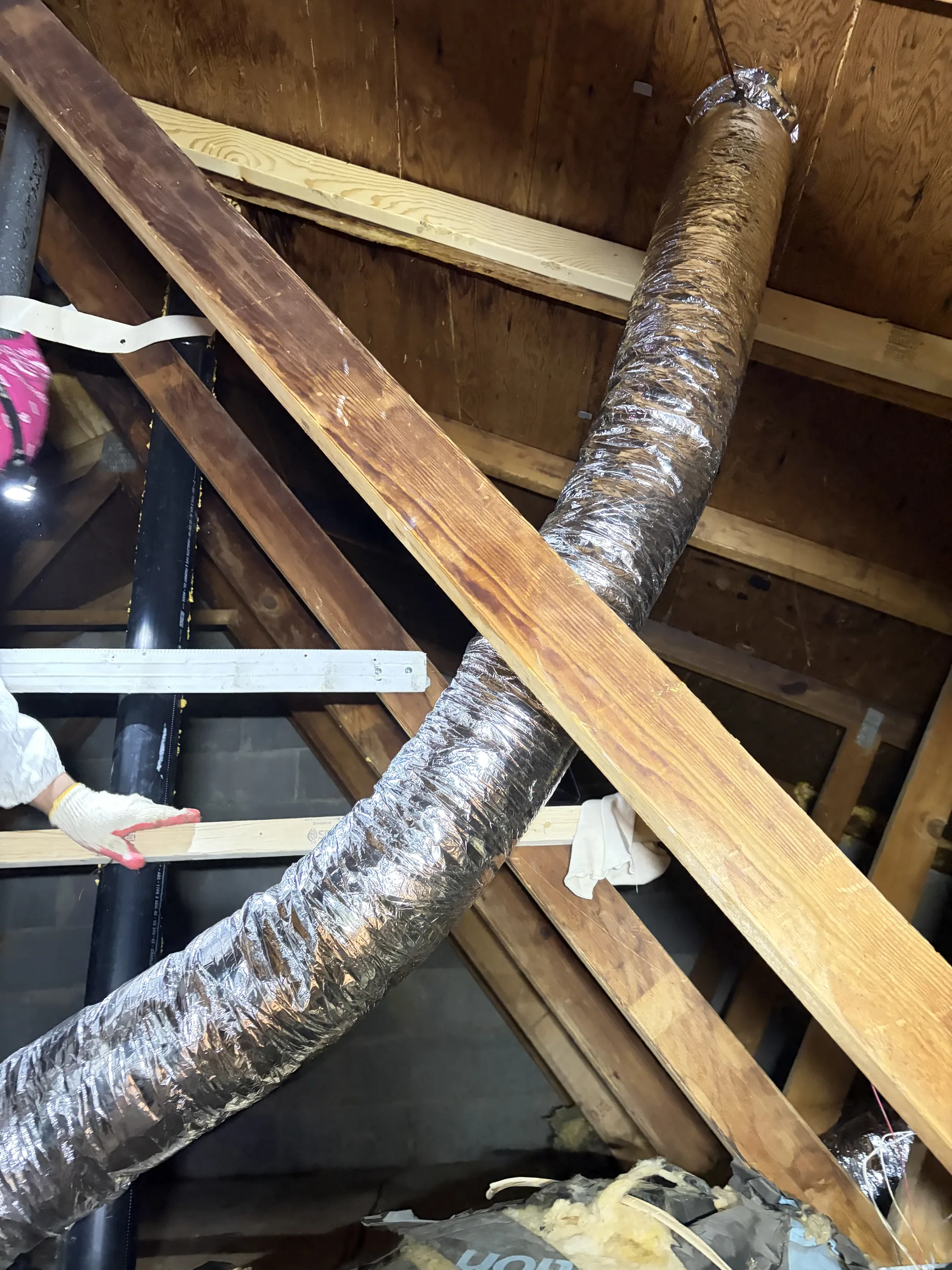 Bathroom exhaust duct routed to a roof connection through attic framing