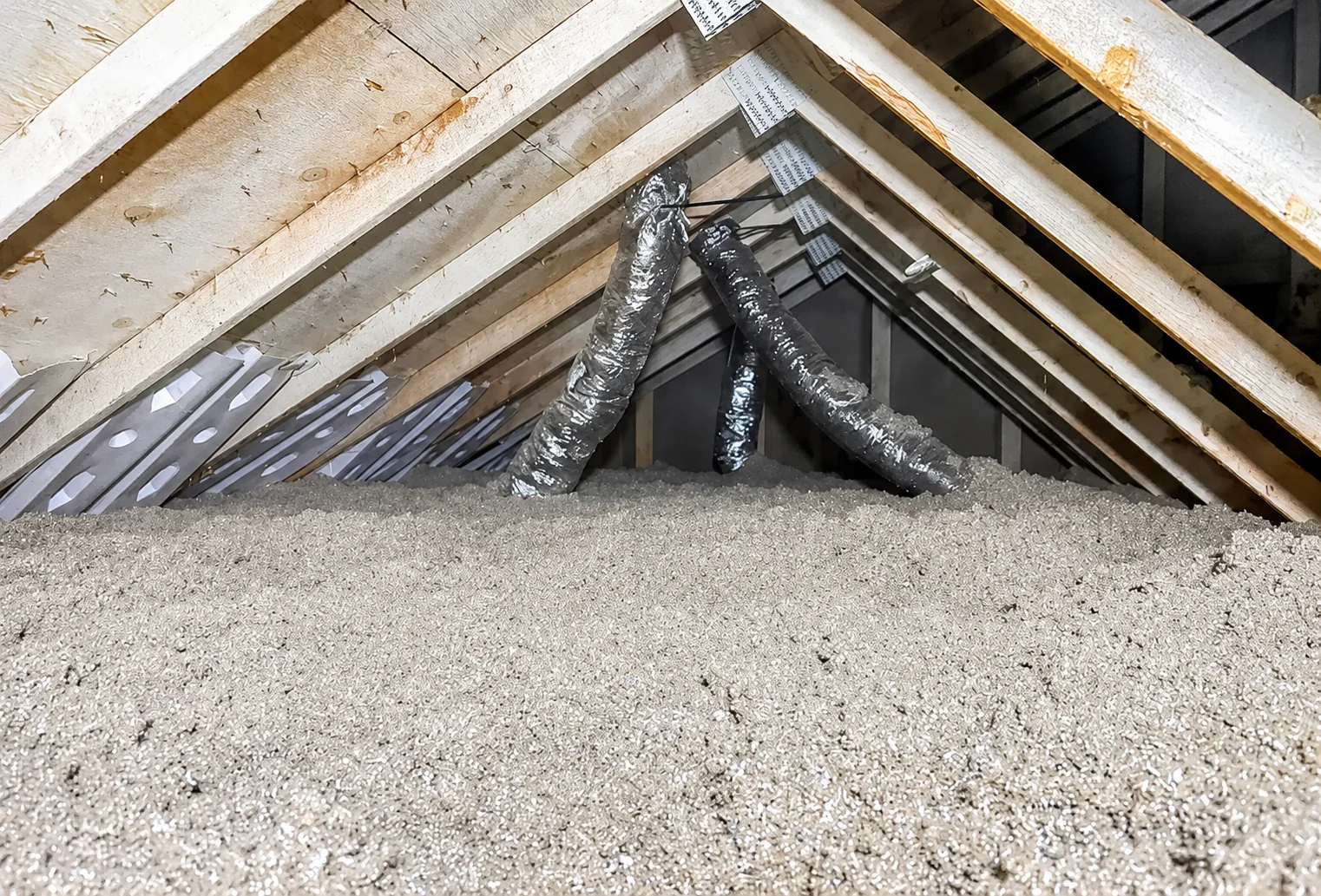 Insulated bathroom exhaust ducts running through an attic toward roof terminations