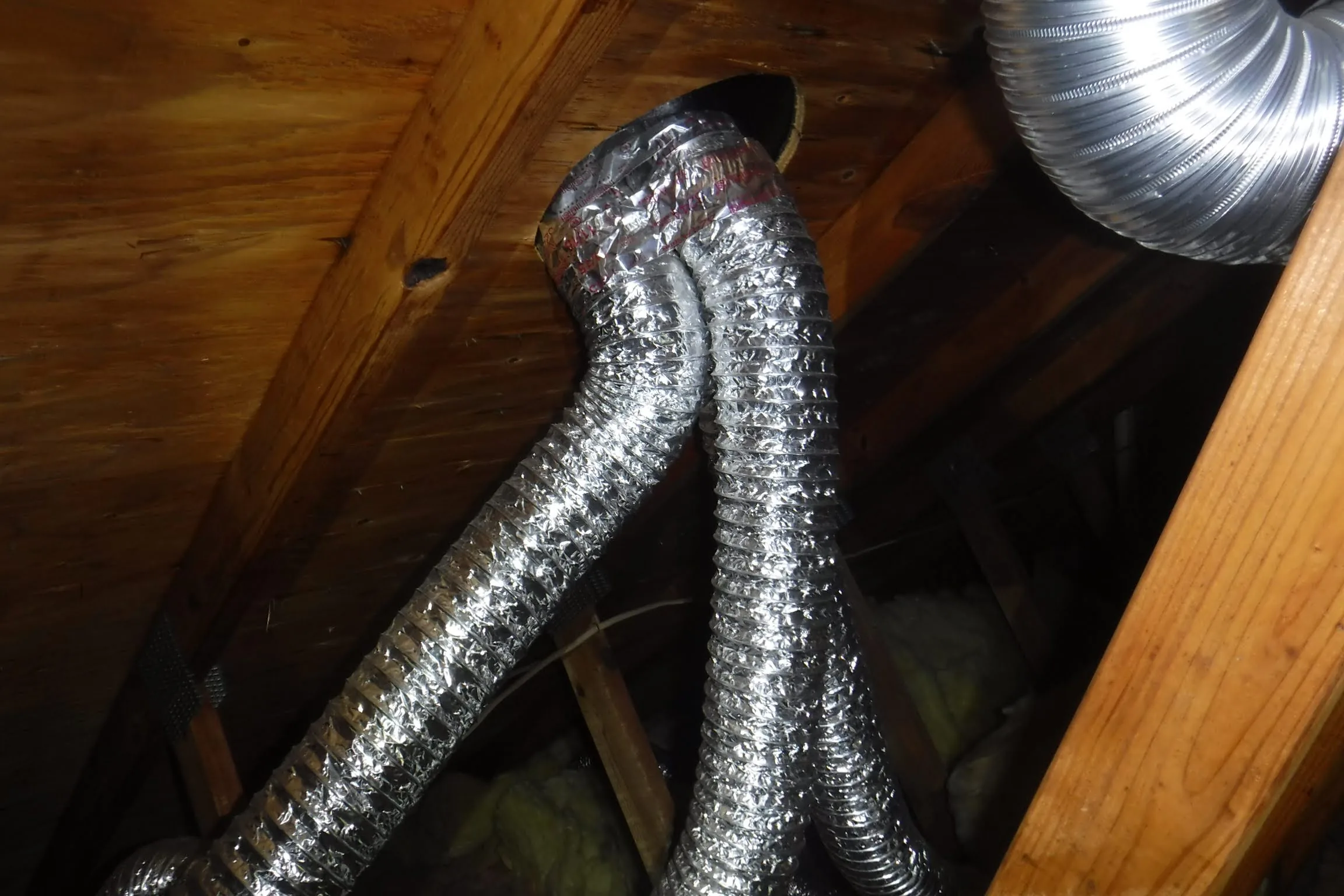 Three bathroom exhaust duct terminations routed through one opening