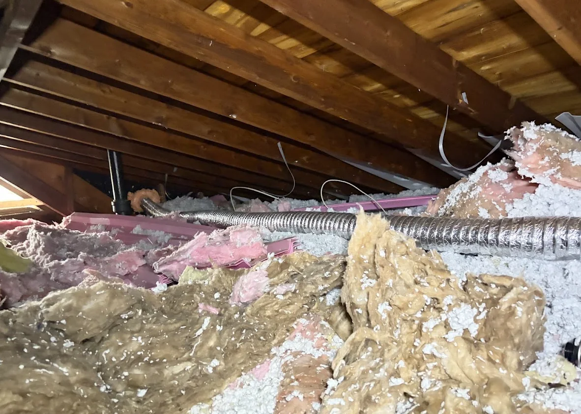 Bathroom exhaust duct following a tight direct run toward a gable wall